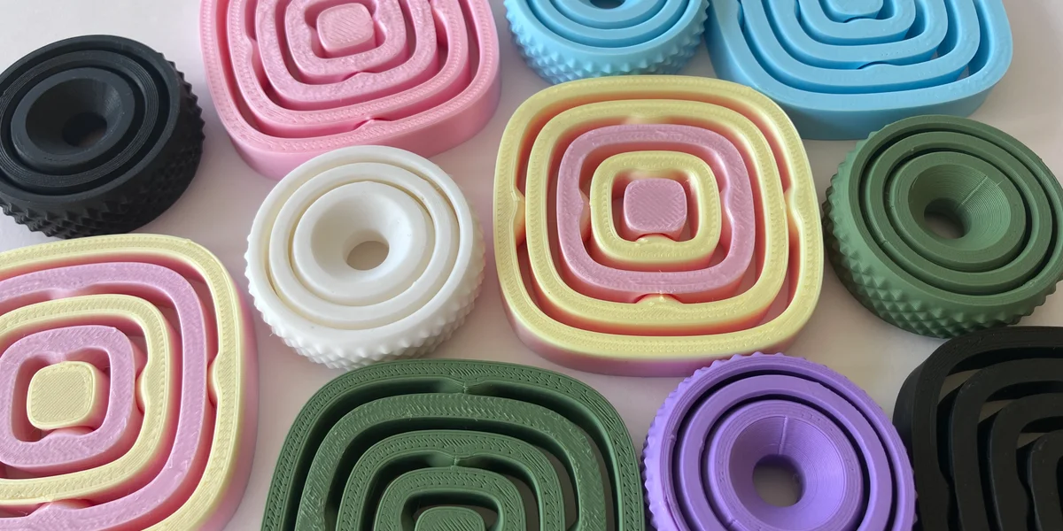 Collection of colourful 3D printed fidget spinners in pastel pink, blue, green, purple and black